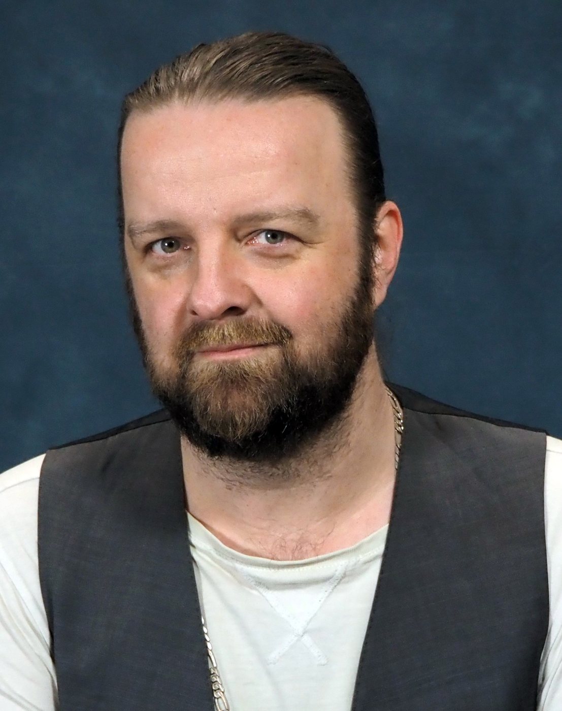 Jay Graham in a grey waistcoat, blue backdrop