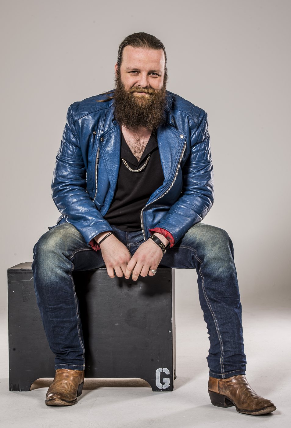 Jay Graham seated, full length, blue leather jacket